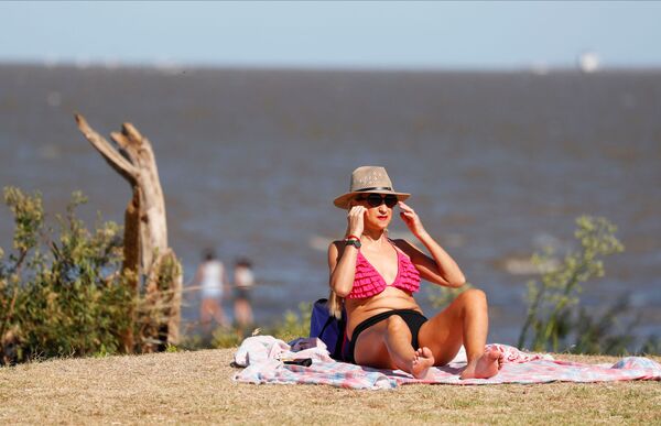 امرأة تستمتع بيومها على شاطئ نهر ريو دي لا بلاتا خلال موجة الحر وسط ارتفاع حالات الإصابة بفيروس كورونا في بوينس آيرس، الأرجنتين، 9 يناير 2022. - سبوتنيك عربي