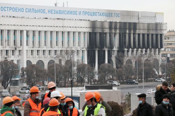 عمال على خلفية مبنى رئيس البلدية أكيمات الذي دمرته النيران في ألماتي، كازاخستان 13 يناير 2021 - سبوتنيك عربي