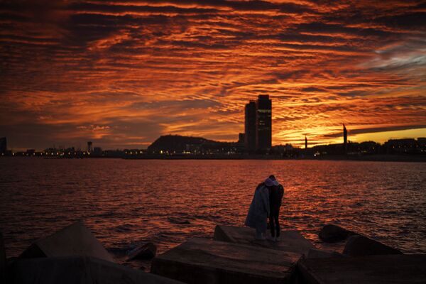 زوجان يشاهدان غروب الشمس على شاطئ في برشلونة، إسبانيا، 8 يناير 2022. - سبوتنيك عربي