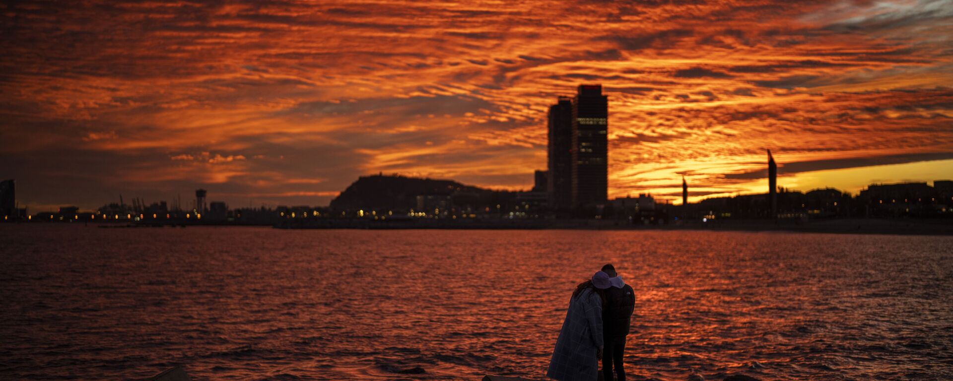 زوجان يشاهدان غروب الشمس على شاطئ في برشلونة، إسبانيا، 8 يناير 2022. - سبوتنيك عربي, 1920, 08.07.2022