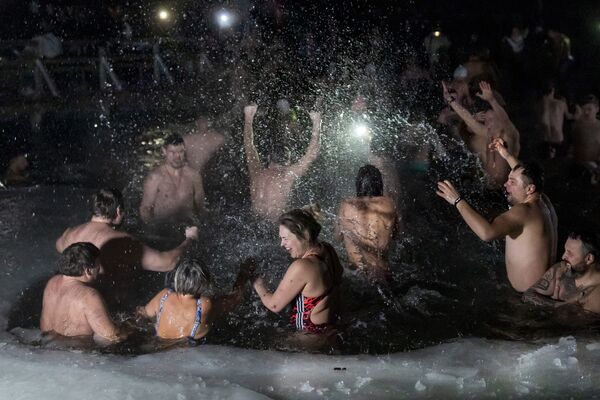 يغطس المسيحيون الأرثوذكس الليتوانيون في المياه الجليدية بعد منتصف الليل بقليل خلال الاحتفال التقليدي بعيد الغطاس في بحيرة بالقرب من فيلنيوس، ليتوانيا، 19 يناير 2022 - سبوتنيك عربي