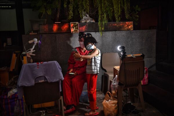طفلة تلتقط صورة سيلفي مع أحد فناني الأوبرا الصينية التقليدية من فرقة ساي يونغ هونغ (Sai Yong Hong) قبل بدء الأوبرا بمناسبة الاحتفالات بالعام القمري الجديد القادم، في مستودع لونغ 1919  في بانكوك، 19 يناير 2022 - سبوتنيك عربي
