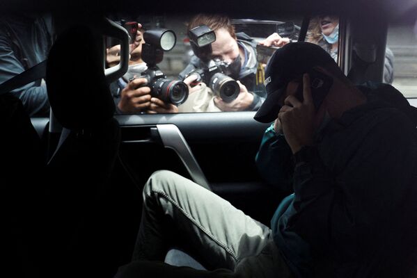 أعضاء وسائل الإعلام يصورون رجلًا مجهول الهوية يغادر موقف السيارات في مكاتب الفريق القانوني للاعب التنس الصربي نوفاك ديوكوفيتش تحت حراسة الشرطة في ملبورن، أستراليا، 15 يناير 2022. - سبوتنيك عربي