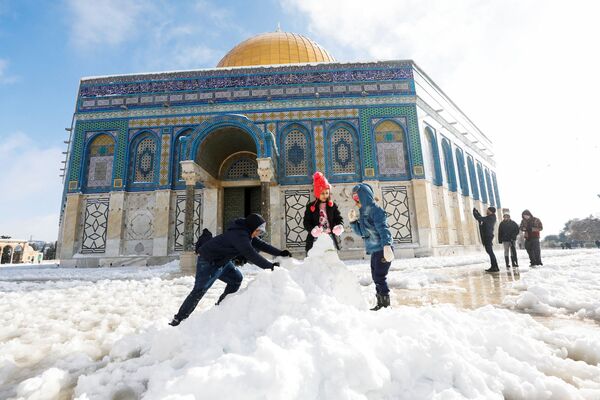 أطفال يصنعون رجل الثلج أمام قبة الصخرة، خلال صباح ثلجي في البلدة القديمة في القدس، 27 يناير  2022. - سبوتنيك عربي