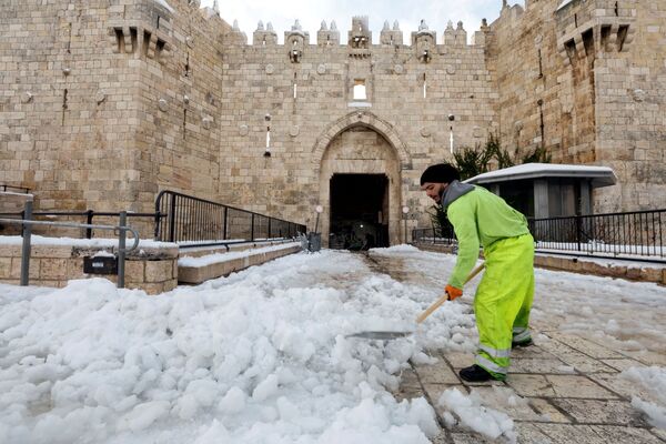 رجل يزيل الثلج أمام باب دمشق في البلدة القديمة في القدس، 27 يناير 2022. - سبوتنيك عربي