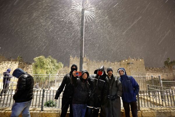 مجموعة من الرجال يلتقطون صورة سيلفي أمام بوابة دمشق أثناء تساقط الثلج في البلدة القديمة في القدس، 26 يناير  2022. - سبوتنيك عربي