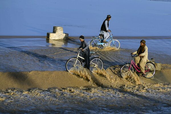 الأولاد يركبون الدراجات في مياه الفيضان المتدفقة على طول مجرى مائي في منطقة دامان في قندهار، أفغانستان 23 يناير 2022. - سبوتنيك عربي