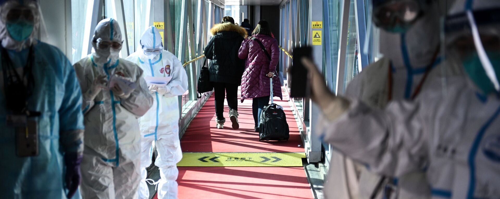 طاقم طبي يرتدي بدلات واقية على جسر تلسكوبي في مطار العاصمة بكين، الصين 1 فبراير 2022 - سبوتنيك عربي, 1920, 03.01.2023