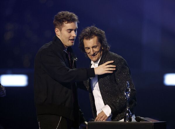 المغني سام فيندر (يسار) يستلم جائزة أفضل مغني روك من مغني روك البريطاني الشهير روني وود خلال حفل توزيع جوائز بريت في O2 أرينا في لندن، بريطانيا 8 فبراير 2022 - سبوتنيك عربي