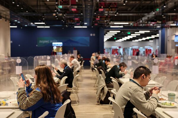 أشخاص يأكلون بينهم حواجز بلاستيكية في قاعة الطعام بالمركز الإعلامي الرئيسي في بكين 2022 دورة الألعاب الاولمبية الشتوية في بكين، الصين، 8 فبراير 2022. - سبوتنيك عربي