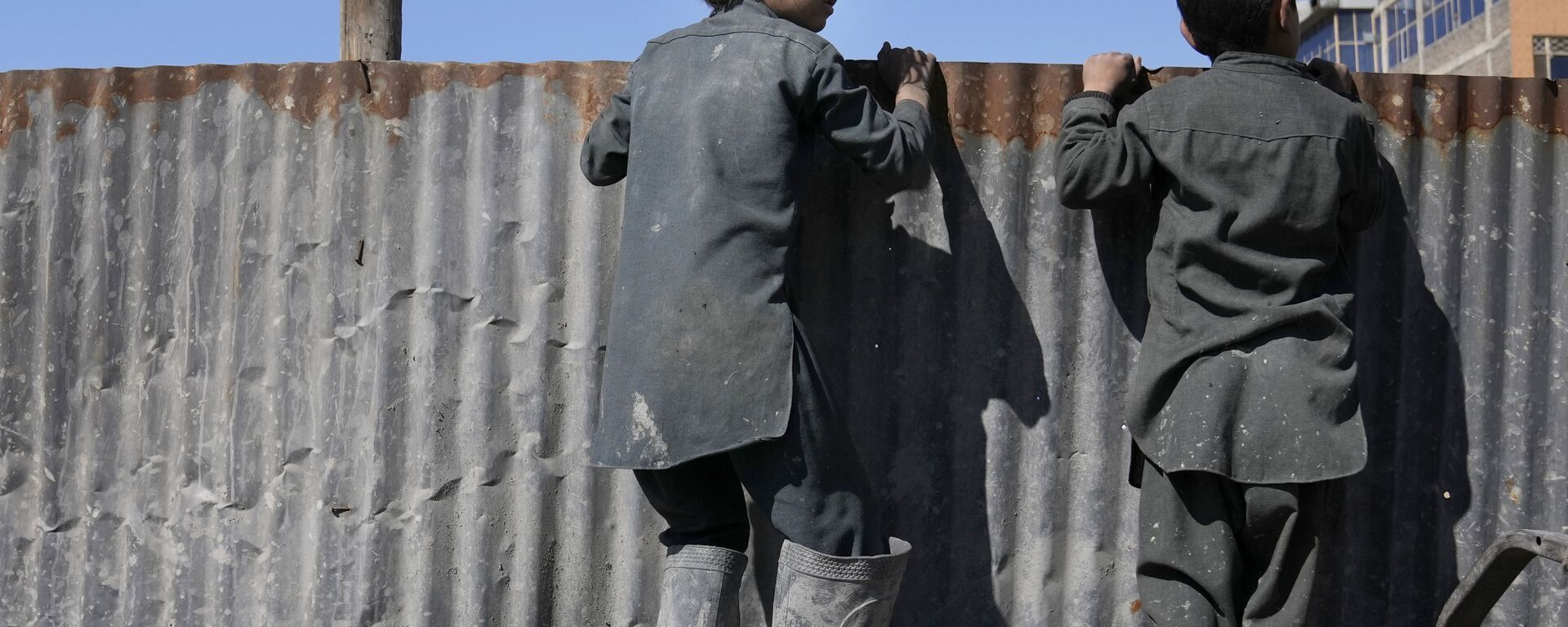 أولاد أفغان ينظرون فوق حاجز حديدي عند الأشخاص الذين يتلقون الإمدادات الغذائية أثناء توزيع المساعدات الإنسانية للعائلات المحتاجة في كابول، أفغانستان، 16 فبراير 2022. - سبوتنيك عربي, 1920, 03.07.2023