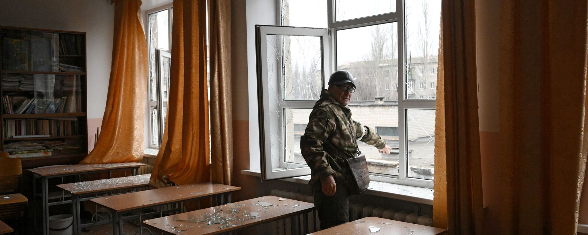 أحد عناصر الشرطة التباع لجمهورية دونيتسك الشعبية في الفصل الدراسي في مدرسة غورلوفكا، الذي تضرر من جراء القصف الأوكراني، 25 فبراير 2022 - سبوتنيك عربي, 1920, 26.02.2022