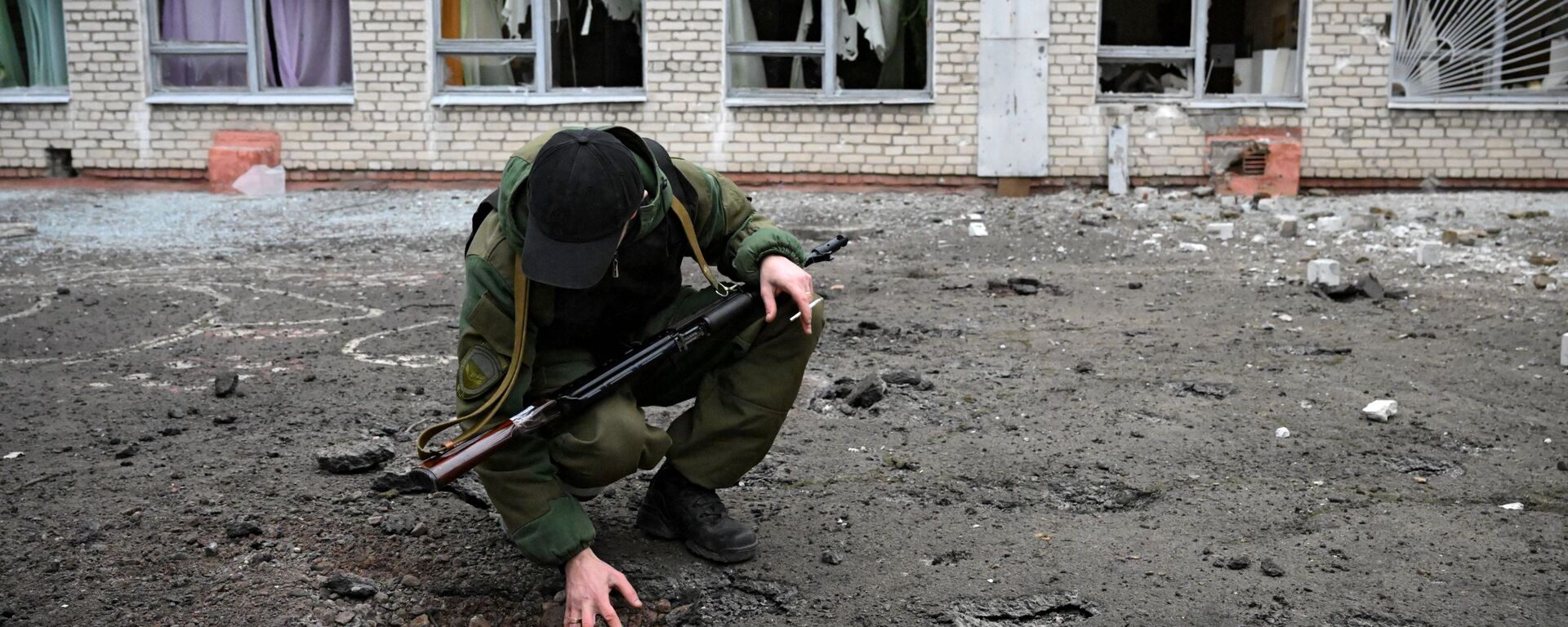 أحد عناصر الشرطة التباع لجمهورية دونيتسك الشعبية في مدرسة غورلوفكا، التي تضررت من جراء القصف الأوكراني، 25 فبراير 2022 - سبوتنيك عربي, 1920, 25.02.2022