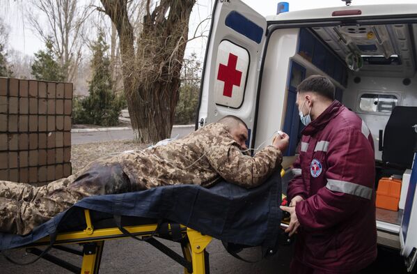 عمال طبيون ينقلون جنديًا مصابًا من الجيش الأوكراني، الذي ألقى سلاحه طوعًا، في أحد المستشفيات في لوغانسك، 25 فبراير 2022 - سبوتنيك عربي