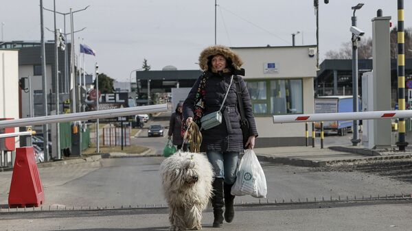 امرأة وكلبها من أوكرانيا يعبران الحدود إلى بولندا عند معبر ميديكا ، 1 مارس 2022. - سبوتنيك عربي