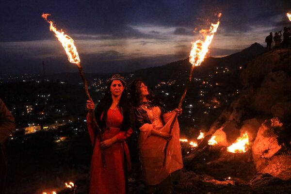 الأكراد العراقيون يحملون المشاعل النارية، احتفالاً بعيد النوروز، وهو احتفال بأول أيام الربيع ورأس السنة الفارسية، في بلدة أكرا بالقرب من دهوك، في كردستان العراق، العراق، 20 مارس 2022. - سبوتنيك عربي