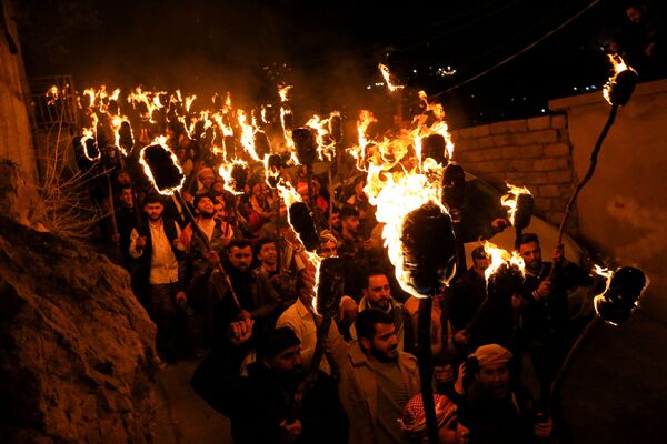 الأكراد العراقيون يحملون المشاعل النارية أثناء احتفالهم بعيد النوروز، وهو احتفال بأول أيام الربيع ورأس السنة الفارسية الجديدة، في بلدة أكرا بالقرب من دهوك، في كردستان العراق، العراق، 20  مارس 2022. - سبوتنيك عربي