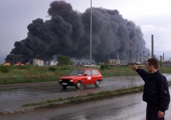 عامل أمن يشير إلى احتراق صهاريج لتكرير النفط في بانشيفو، على بعد حوالي 16 كيلومترًا  شمال بلغراد، 18 أبريل/ نيسان 1999. - سبوتنيك عربي