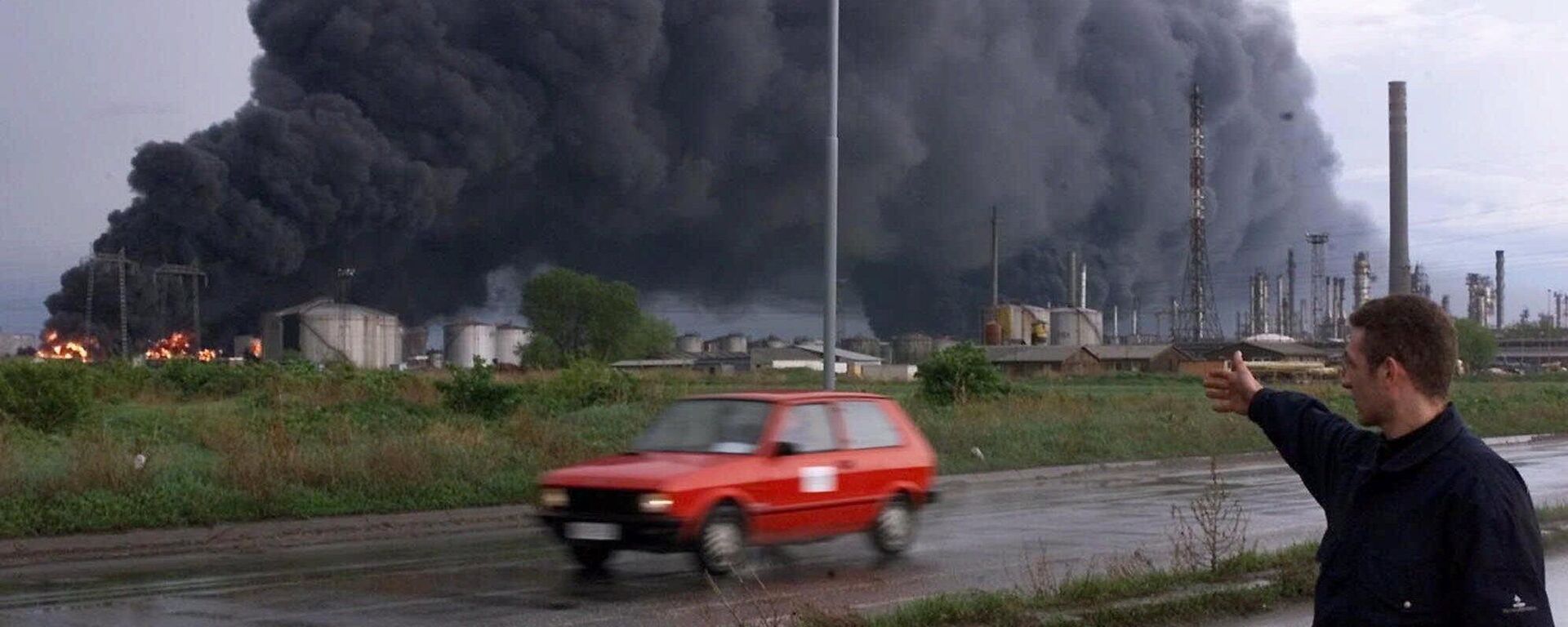 عامل أمن يشير إلى احتراق صهاريج لتكرير النفط في بانشيفو، على بعد حوالي 16 كيلومترًا  شمال بلغراد، 18 أبريل/ نيسان 1999. - سبوتنيك عربي, 1920, 05.05.2023