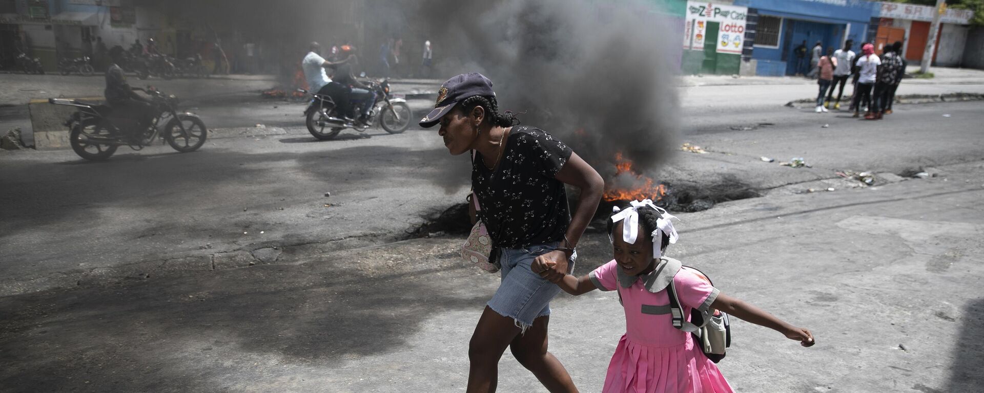 امرأة تقود طفلًا أمام مظاهرة ضد العنف المتزايد في بورت أو برنس، هايتي، 29 مارس  2022. - سبوتنيك عربي, 1920, 03.05.2022