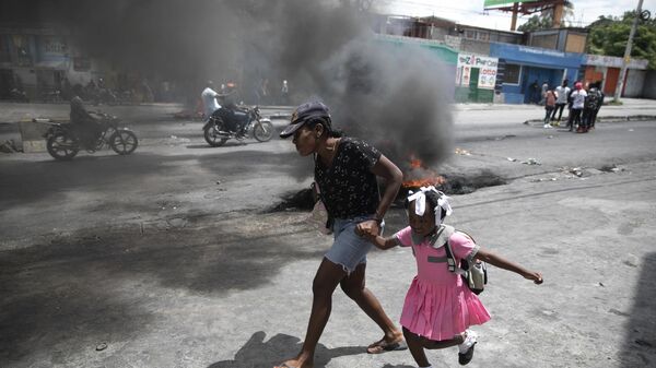 امرأة تقود طفلًا أمام مظاهرة ضد العنف المتزايد في بورت أو برنس، هايتي، 29 مارس  2022. - سبوتنيك عربي