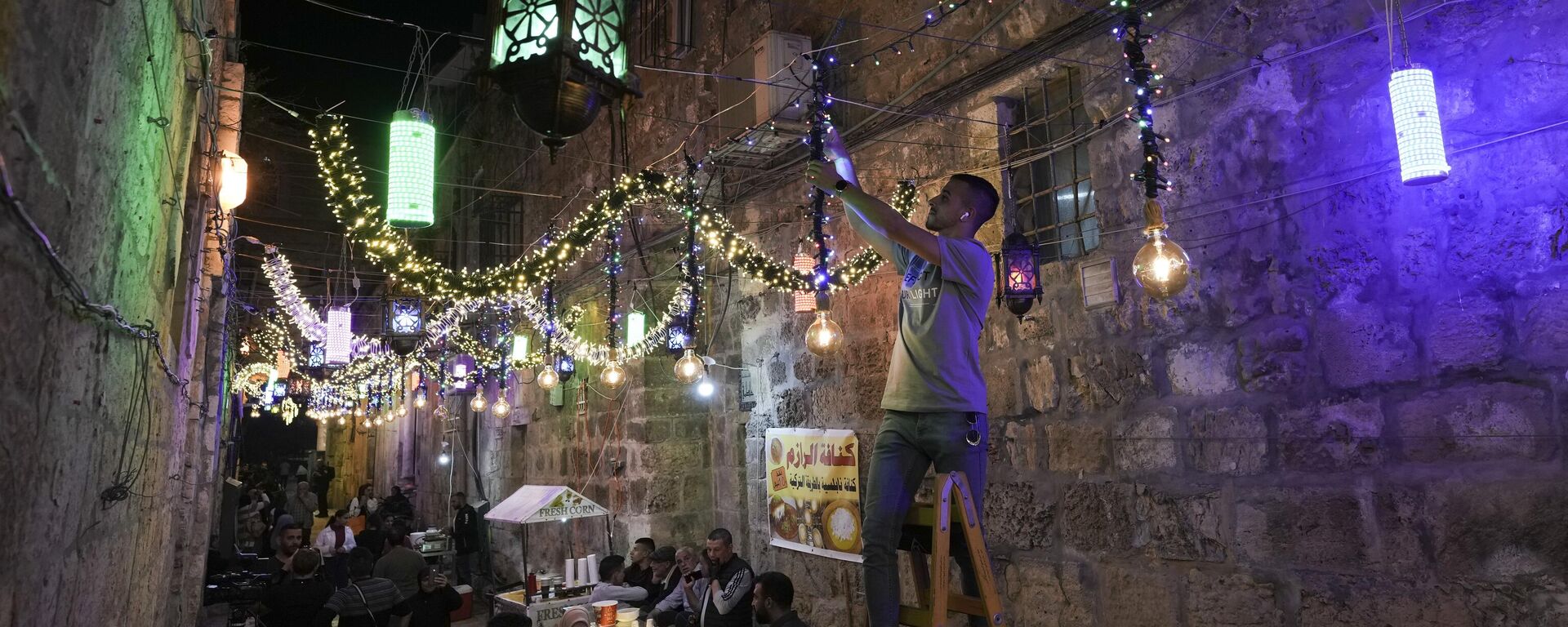 رجل فلسطيني يعلق أضواء زخرفية استعدادًا لشهر رمضان المبارك، في شوارع البلدة القديمة في القدس، 1 أبريل 2022. - سبوتنيك عربي, 1920, 26.04.2022