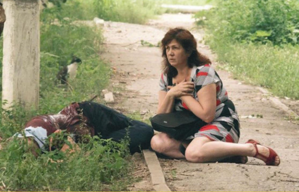 يوليو/ حزيران 2014، لوغانسك. امرأة في حالة صدمة بجوار أحد ضحايا قصف مدفعي للقوات المسلحة الأوكرانية. - سبوتنيك عربي