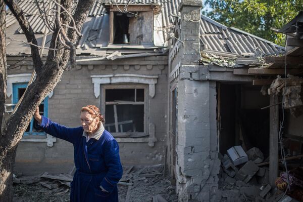  أغسطس/آب 2015. امرأة أمام بيت دمره قصف أوكراني في بلدة ألكساندروفكا بمقاطعة دونيتسك. - سبوتنيك عربي