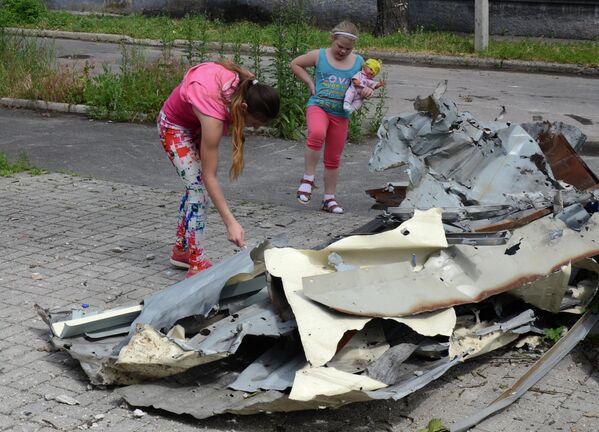 يونيو/ حزيران 2017. أطفال يتفقدون كساء المبنى الذي أصابه الدمار في قصف أوكراني استهدف حي كييفسكي لمدينة دونيتسك. - سبوتنيك عربي