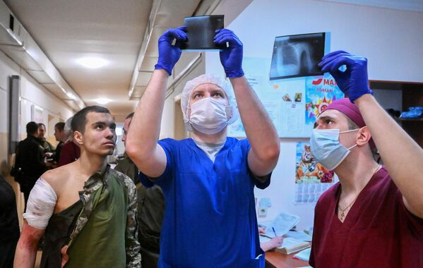 المسعفون في مستشفى منطقة نوفوازوفسكايا المركزية يفحصون صور الأشعة السينية لمريض. على اليسار: جندي من القوات المسلحة الأوكرانية استسلم في ماريوبول. قدم أطباء المستشفى المساعدة الطبية للسجين. - سبوتنيك عربي