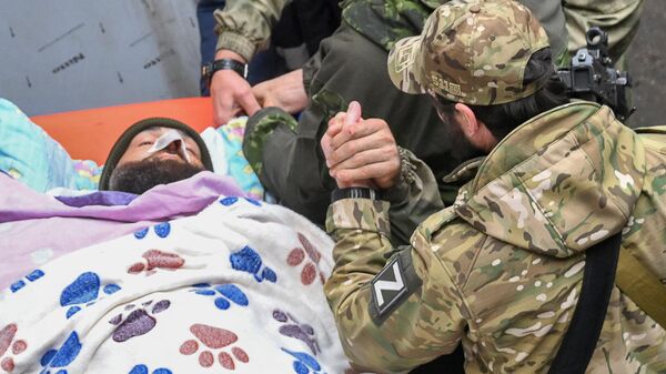 جندي روسي يدعم زميله الجريح ، الذي يُنقل على نقالة إلى سيارة إسعاف من مستشفى منطقة نوفوازوفسك المركزية لإجلائه لاحقًا إلى روسيا. - سبوتنيك عربي