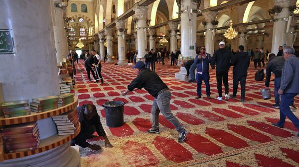 فلسطينيون ينظفون المسجد بعد الاشتباكات مع الشرطة الفلسطينية في المسجد الأقصى في القدس الشرقية المحتلة، 15 أبريل 2022 - سبوتنيك عربي