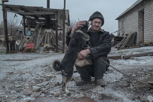 أالكسندر فاسيليف، البالغ من العمر 62 عامًا، مع كلبه، هو أحد آخر سكان قرية نوفومارييفكا في منطقة دونيتسك، والتي انتهى بها المطاف على خط التماس بين طرفي النزاع في دونباس.في هذه الصورة لفاليري ميلنيكوف من سلسلة &quot;Gray Zone&quot; (المنطقة الرمادية)، التي فازت بالجائزة الكبرى لمسابقة الصور Intarget Photolux Award لعام 2019. - سبوتنيك عربي