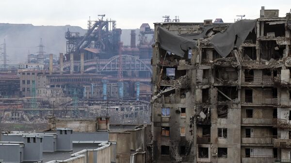 منظر لمبنى سكني مدمر على خلفية مصنع آزوفستال في ماريوبول، أوكرانيا 23 أبريل 2022 - سبوتنيك عربي