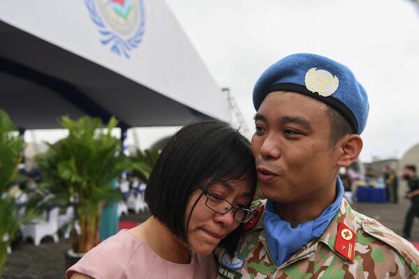 أحد أفراد القوة الفيتنامية المشاركة في بعثة الأمم المتحدة لحفظ السلام في جنوب السودان يواسي زوجته قبل مغادرته هانوي في 27 أبريل 2022. - سبوتنيك عربي