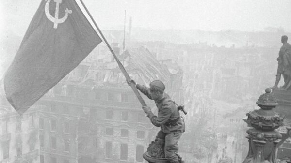 أحد جنود الجيش الأحمر ينصب راية النصر فوق مبنى البرلمان الألماني في 1 مايو/أيار 1945 - سبوتنيك عربي