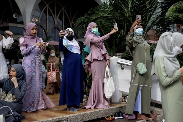 نساء يلتقطن صورًا بعد صلاة الفجر في مؤسسة مسجد المركز الإسلامي في تايلاند خلال احتفالات عيد الفطر في بانكوك، 2 مايو 2022. - سبوتنيك عربي
