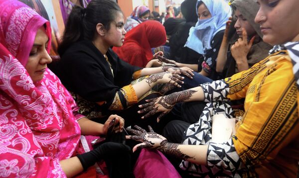 أخصائيو تجميل باكستانيون يرسمون أيدي العملاء بالحناء التقليدية استعدادًا لعطلة عيد الفطر القادمة، في صالون تجميل في كراتشي، باكستان 2 مايو 2022. - سبوتنيك عربي