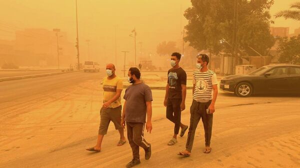 عراقيون يسيرون في أحد شوارع مدينة بغداد، خلال عاصفة رملية قوية، العراق 5 مايو 2022 - سبوتنيك عربي