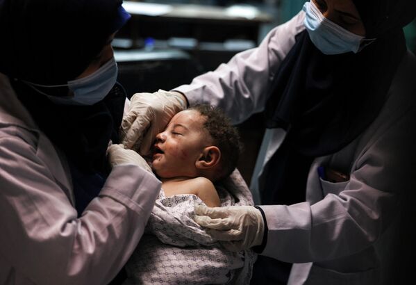 ممرضة تحمل طفلاً انتشل حياً من تحت الأنقاض في غارة جوية في غزة، طاع غزة، فلسطين - سبوتنيك عربي