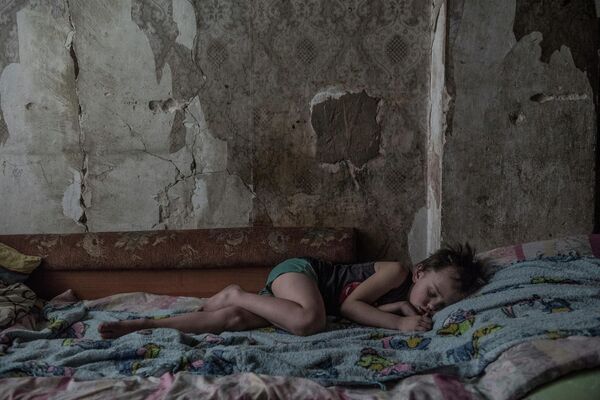 الفتى روسلان بيختين،البالغ من العمر سبع سنوات، في منزل بالقرب من خط التماس في ضواحي دونيتسك.صورة من سلسلة &quot;Gray Zone&quot; الحائزة على الجائزة الكبرى لمسابقة الصور Intarget Photolux لعام 2019. - سبوتنيك عربي