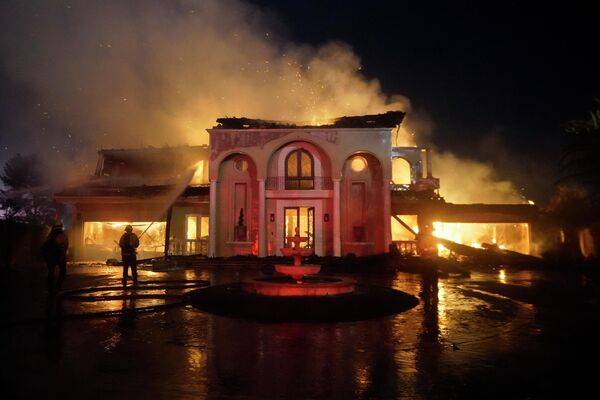 يعمل رجال الإطفاء على إخماد هيكل مشتعل أثناء حريق غابات الأربعاء 11 مايو 2022، في لاجونا نيجيل، كاليفورنيا. - سبوتنيك عربي