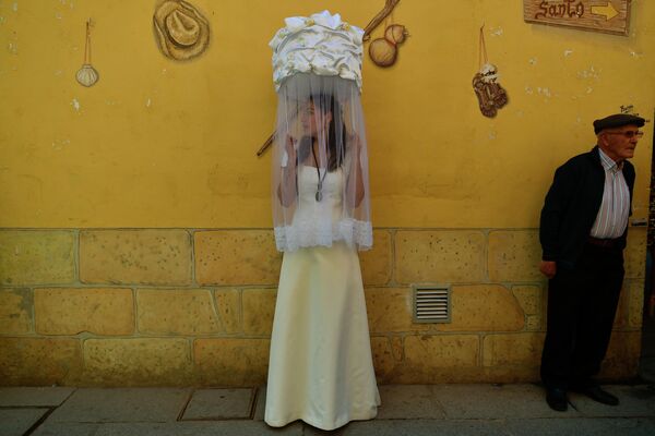 إحدى المشاركات في حفل &#x27;&#x27;لاس دونسيلاس&#x27;&#x27; (عوانس)، تحمل سلة مغطاة بقطعة قماش بيضاء تنقل رغيف خبز على رأسها، خلال &quot;موكب خبز القديس&quot;، حفل تكريم القديس دومينغو دي لا كالزادا (1019-1109) الذي ساعد الفقراء والحجاج، في سانتو دومينغو دي لا كالزادا، شمال إسبانيا 11 مايو 2022. لقد مر عامان منذ آخر إجراء بسبب قيود كوفيد-19. - سبوتنيك عربي