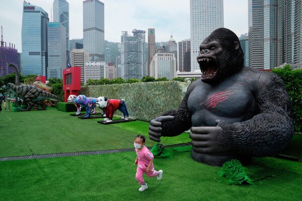 فتاة ترتدي كمامة، تهرب من لعبة غوريلا في حديقة في هونغ كونغ، 9 مايو 2022. - سبوتنيك عربي