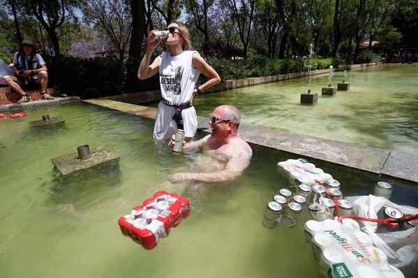 مشجعو أينتراخت يشربون البيرة أثناء اسجمامهم في نافورة مياه في حديقة وسط مدينة إشبيلية، إسبانيا، 18 مايو 2022.  - سبوتنيك عربي