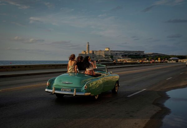فتيات يركبن سيارة أمريكية كلاسيكية في العاصمة الكوبية هافانا، 16 مايو عام 2022 - سبوتنيك عربي
