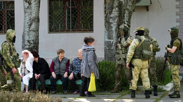 كبار السن من السكان المحليين يتحدثون إلى مجموعة من الجنود الروس في خيرسون، منطقة خيرسون، جنوب أوكرانيا، 20 مايو 2022. - سبوتنيك عربي