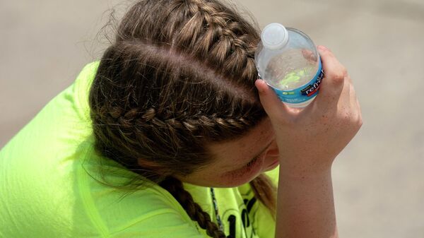 زائرة تحمل زجاجة ماء وترفعها إلى رأسها لتبرده في نصب لنكولن التذكاري في واشنطن العاصمة، الولايات المتحدة 21 مايو 2022. - سبوتنيك عربي