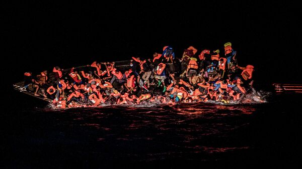 صورة تظهر لحظة سقوط العشرات من المهاجرين في المياه بينما يحولون التشبث بجانب قارب مقلوب قبالة مياه تونس في وقت مبكر 25 مايو 2022 - سبوتنيك عربي