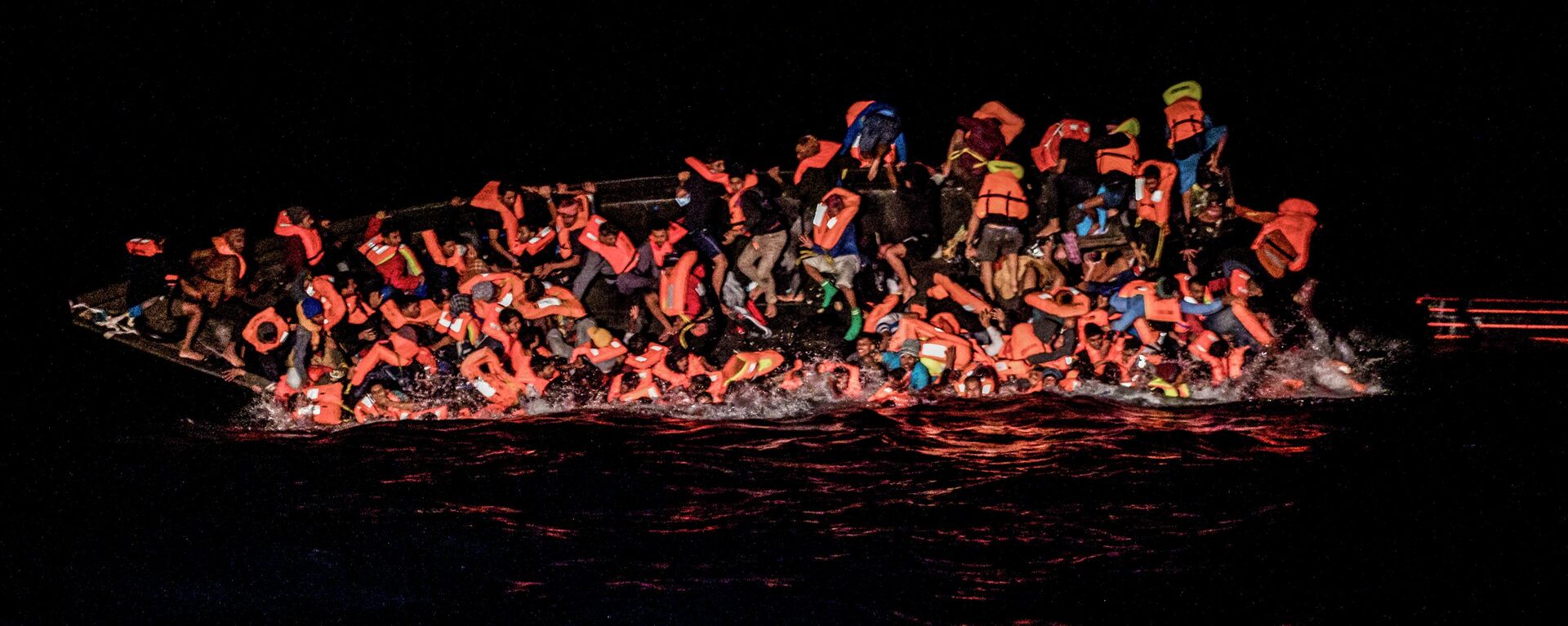 صورة تظهر لحظة سقوط العشرات من المهاجرين في المياه بينما يحولون التشبث بجانب قارب مقلوب قبالة مياه تونس في وقت مبكر 25 مايو 2022 - سبوتنيك عربي, 1920, 28.01.2024
